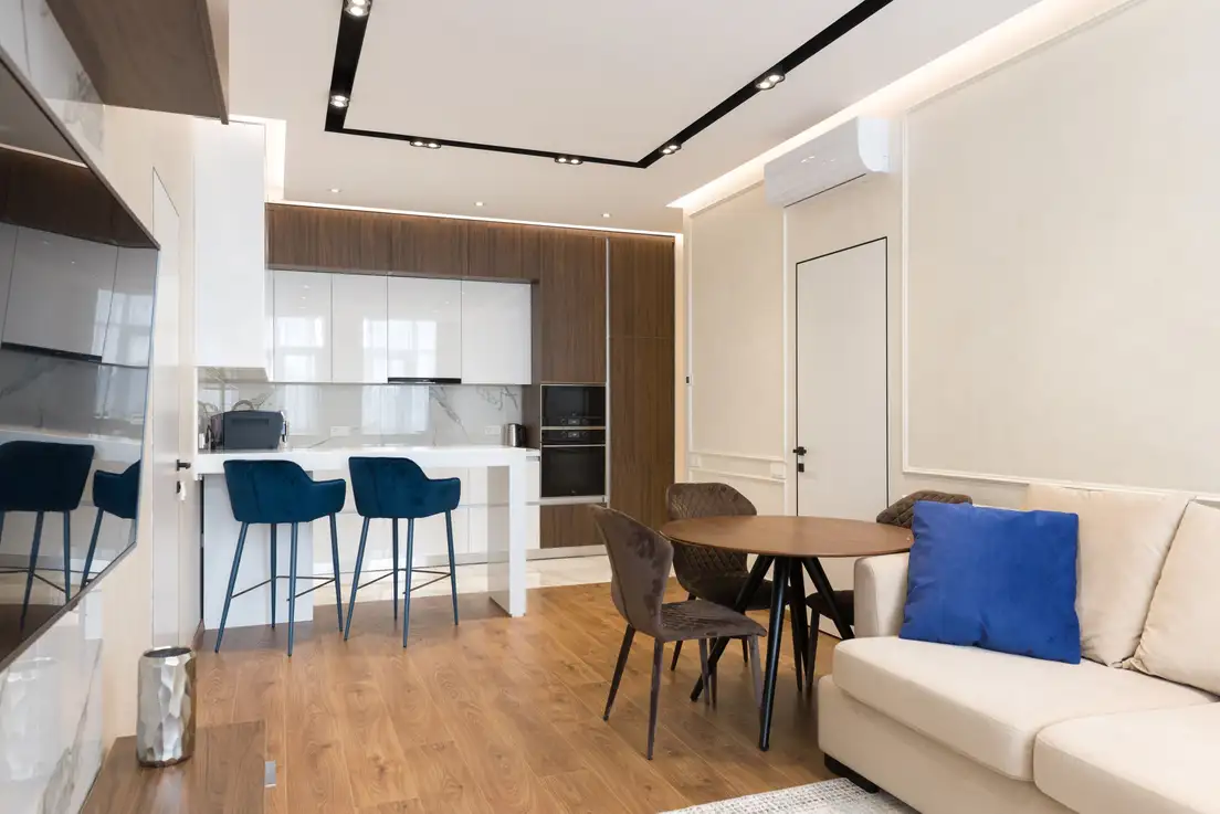 A cream sofa with its back facing a small round dining table and chairs, separating the living area from the dining space and kitchen