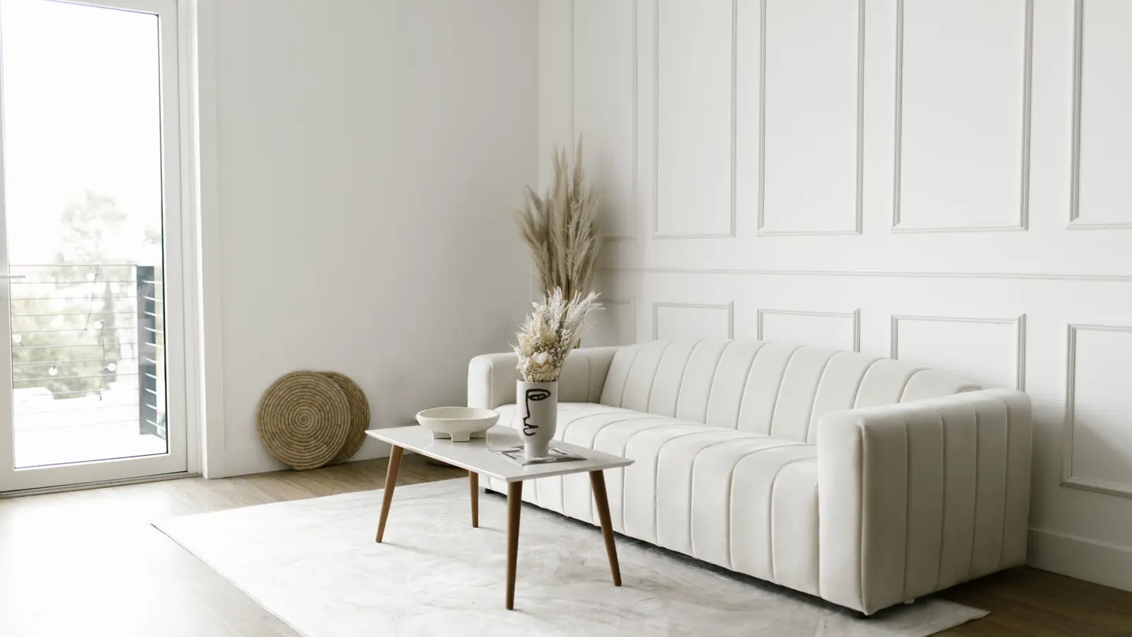 A cream channel-tufted low-profile sofa with clean lines against a paneled wall