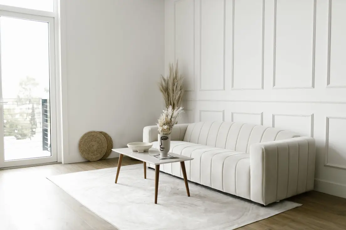 A cream channel-tufted low-profile sofa with clean lines against a paneled wall