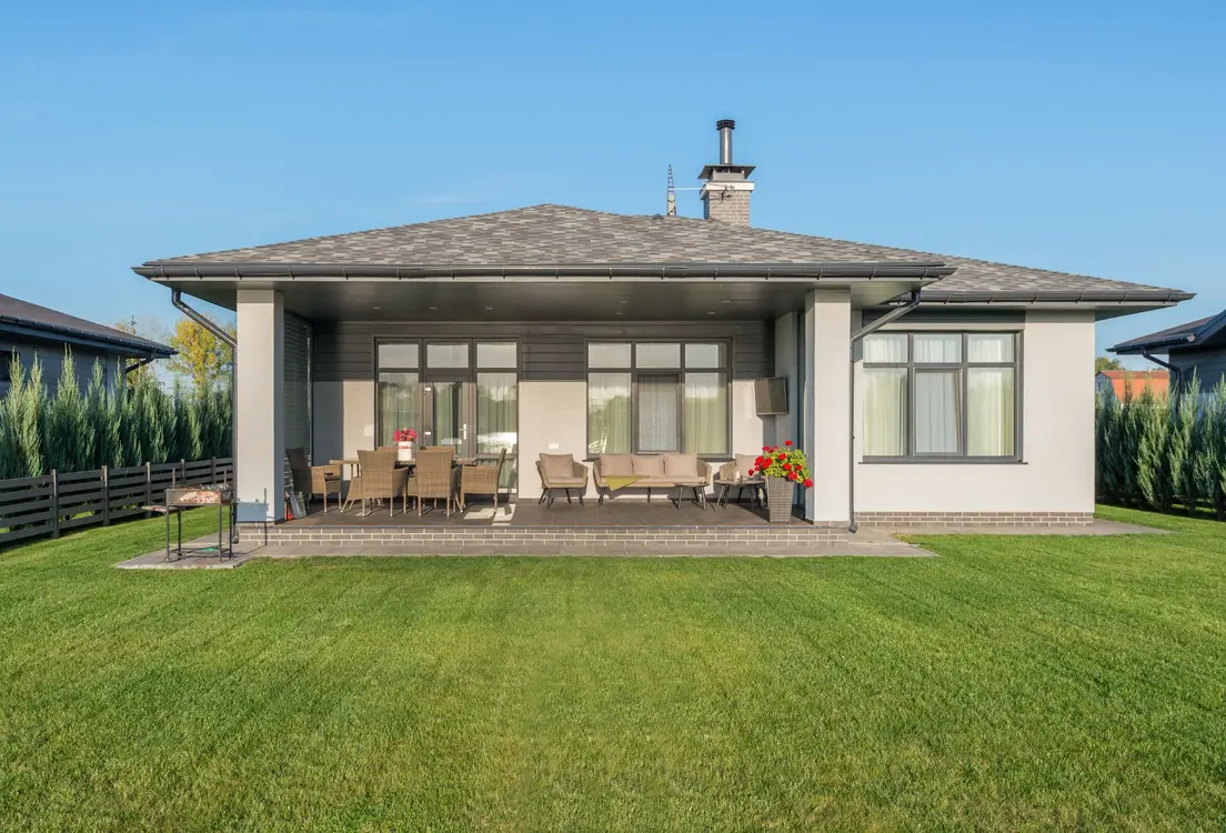 A house with a solid tiled roof extending over a covered patio dining area