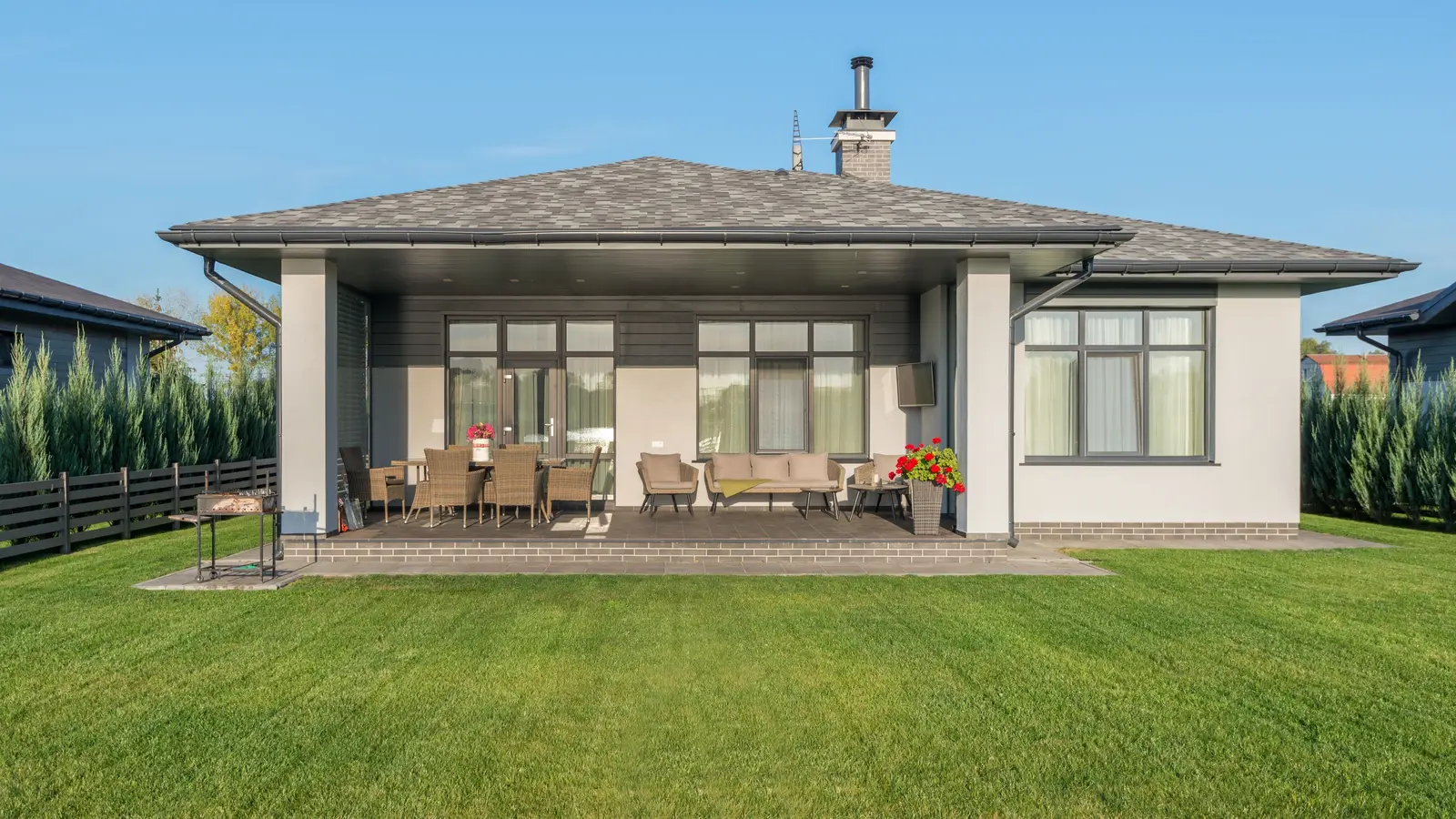 A house with a solid tiled roof extending over a covered patio dining area