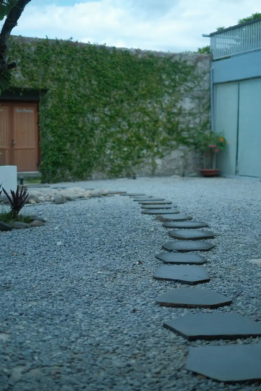 Flagstone stepping stones set into a gravel pathway near a garden wall