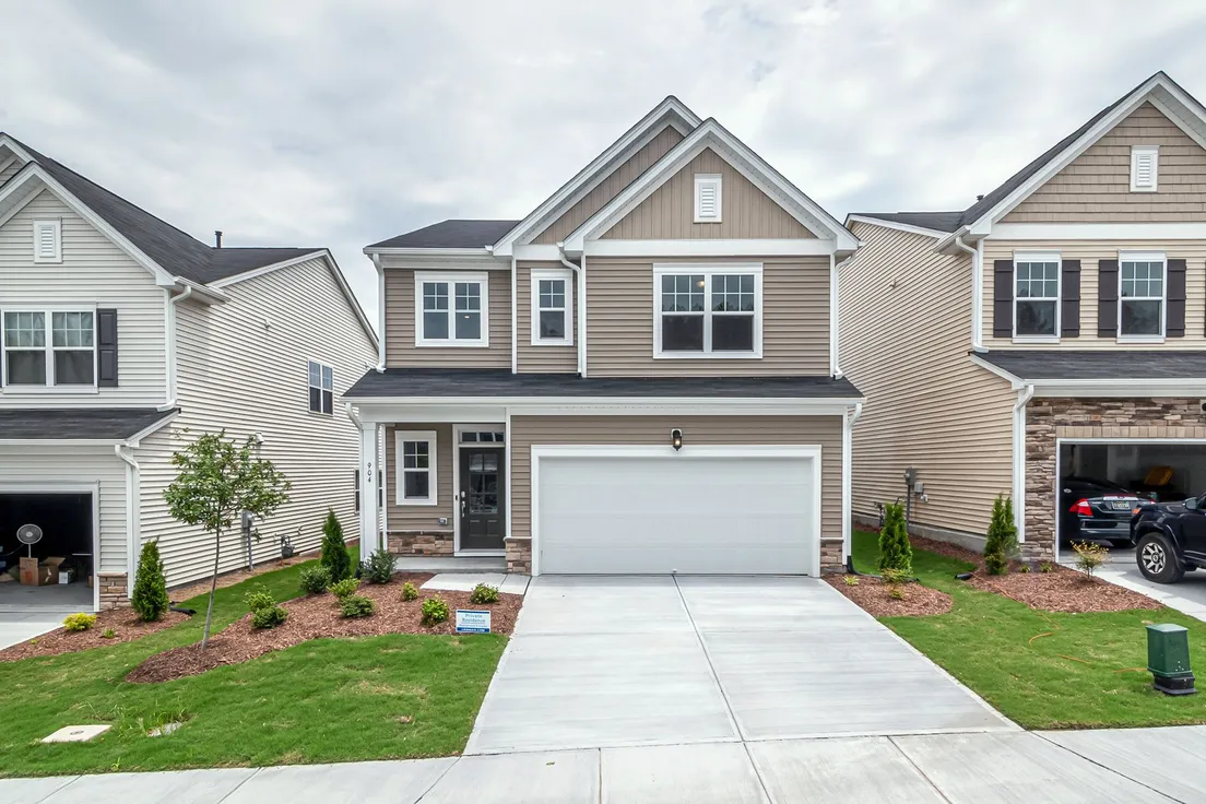 A beige house exterior with a natural stone accent base as the only textured material on the facade