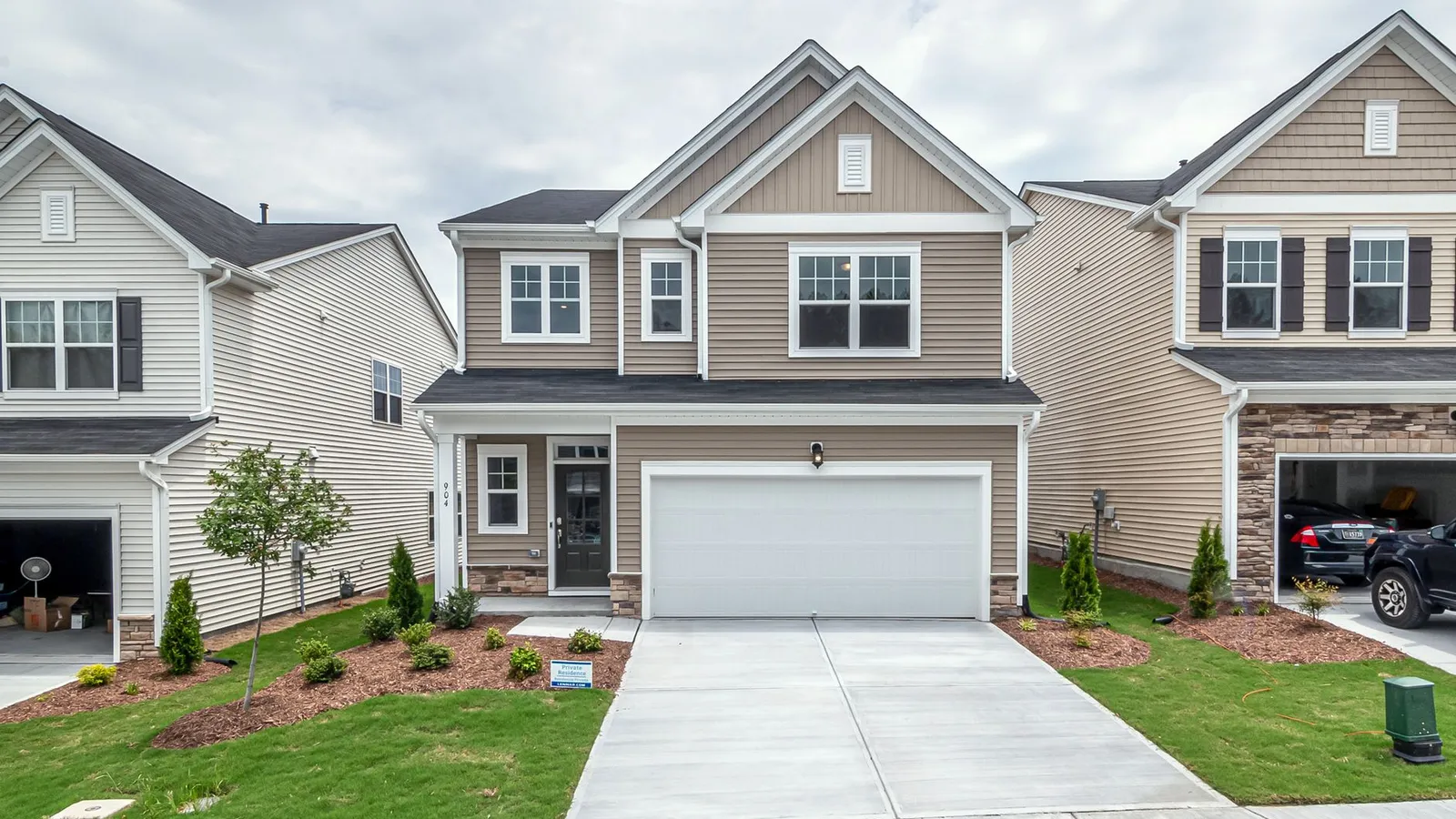 A beige house exterior with a natural stone accent base as the only textured material on the facade