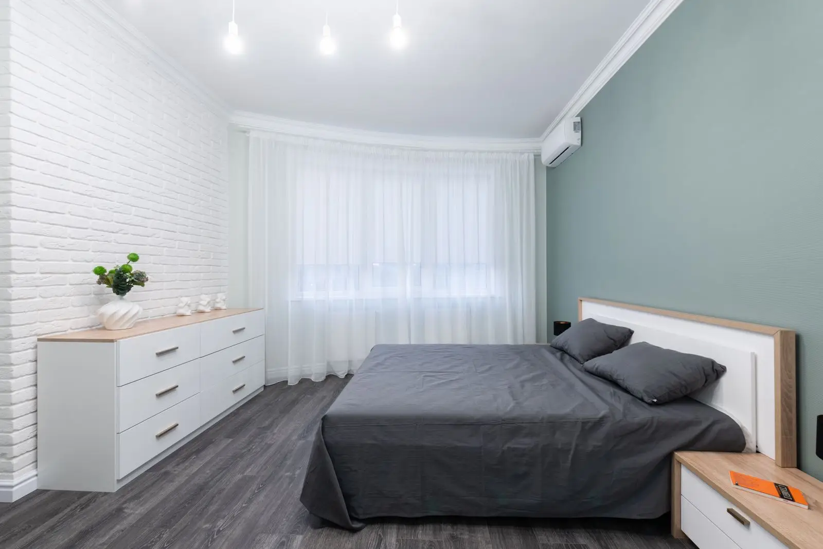A low platform storage bed with a wood frame in a bright small apartment bedroom, a multifunctional furniture piece with drawer storage