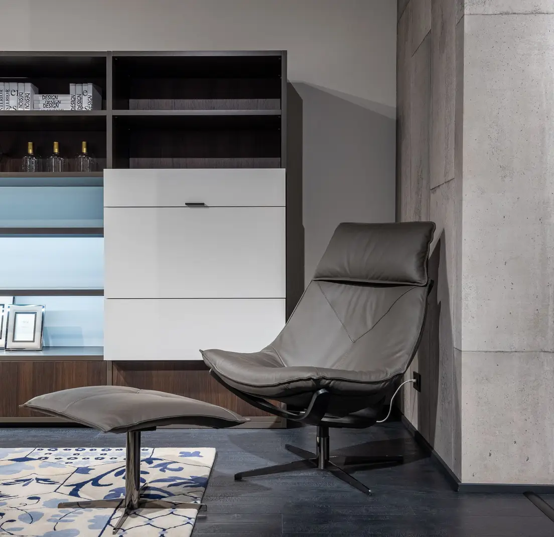 A living room chair beside a storage ottoman used instead of a coffee table, a small apartment idea for dual-purpose furniture