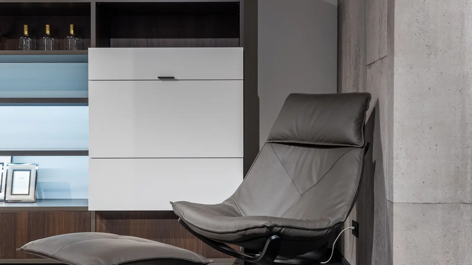A living room chair beside a storage ottoman used instead of a coffee table, a small apartment idea for dual-purpose furniture