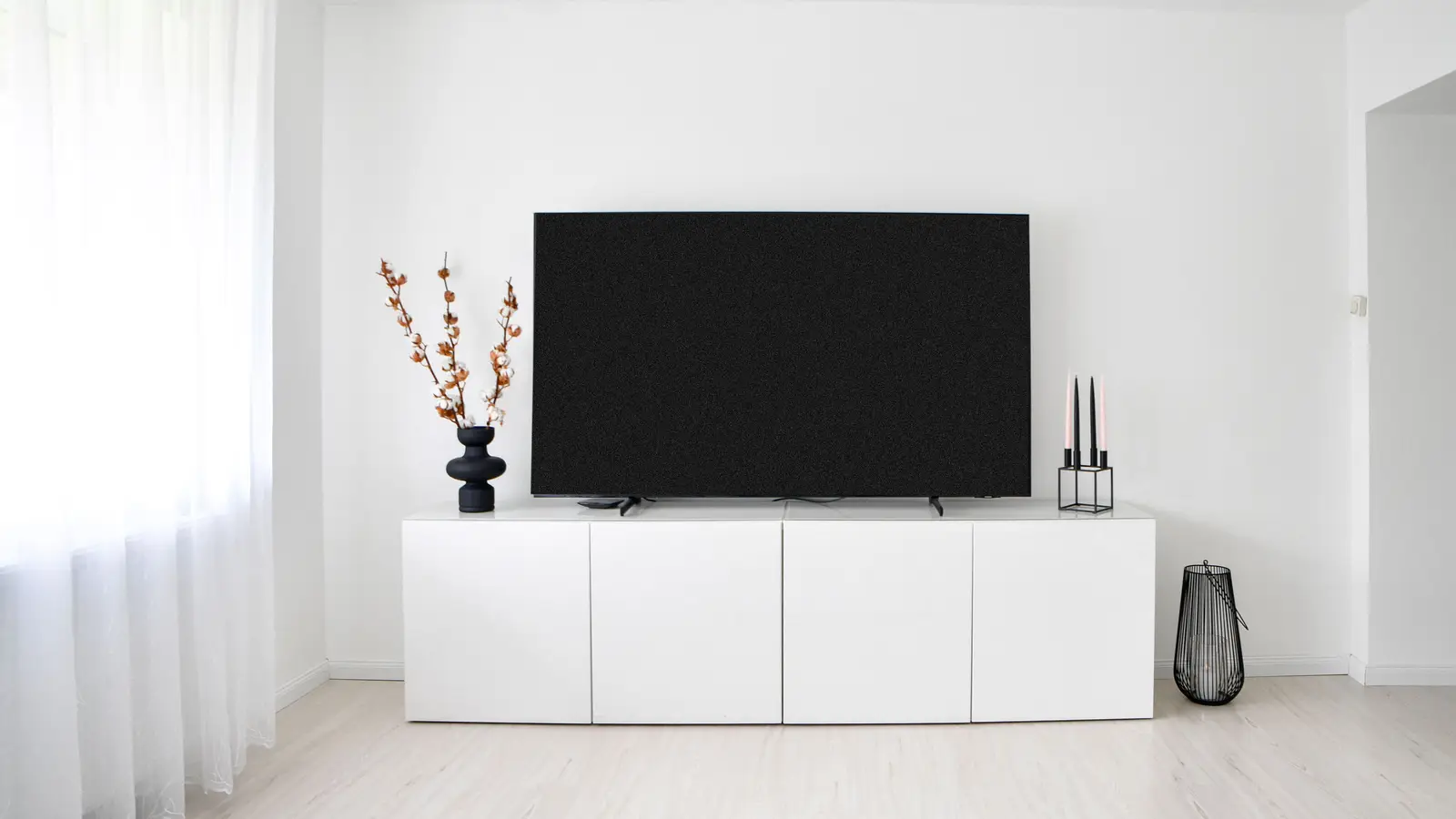 A low white closed-door media console in a minimalist living room hiding clutter
