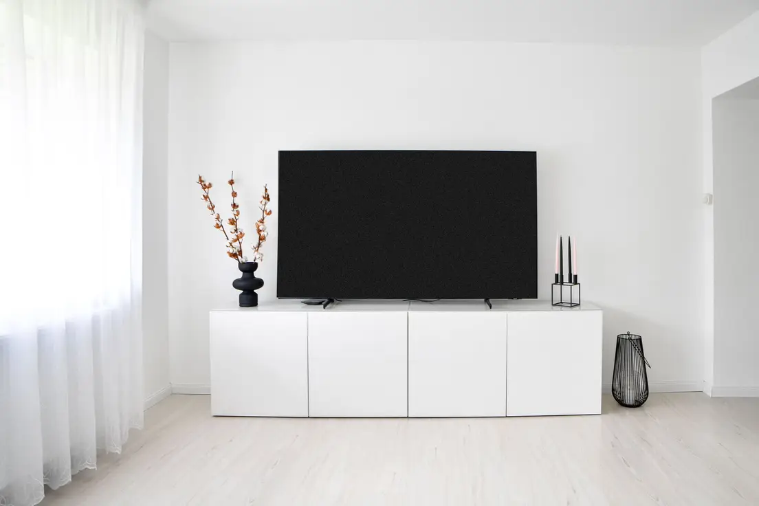 A low white closed-door media console in a minimalist living room hiding clutter