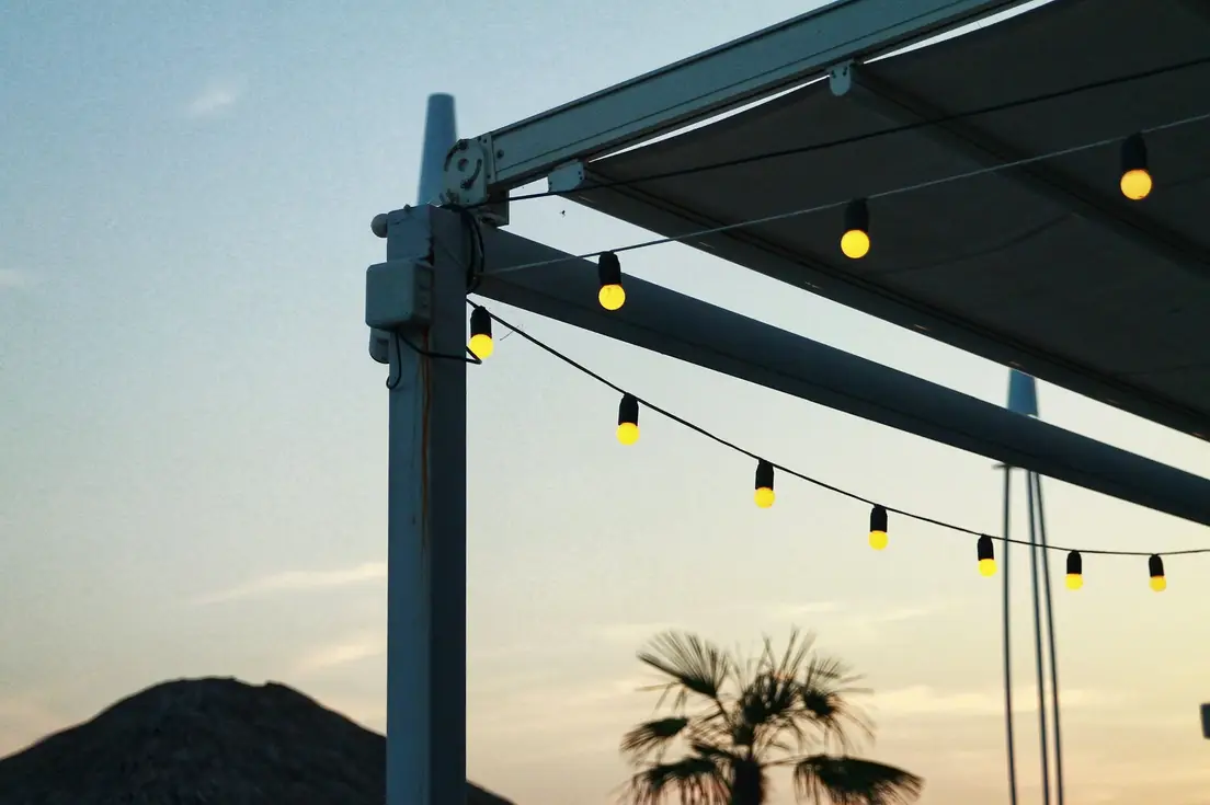 String lights hanging along a patio structure at sunset