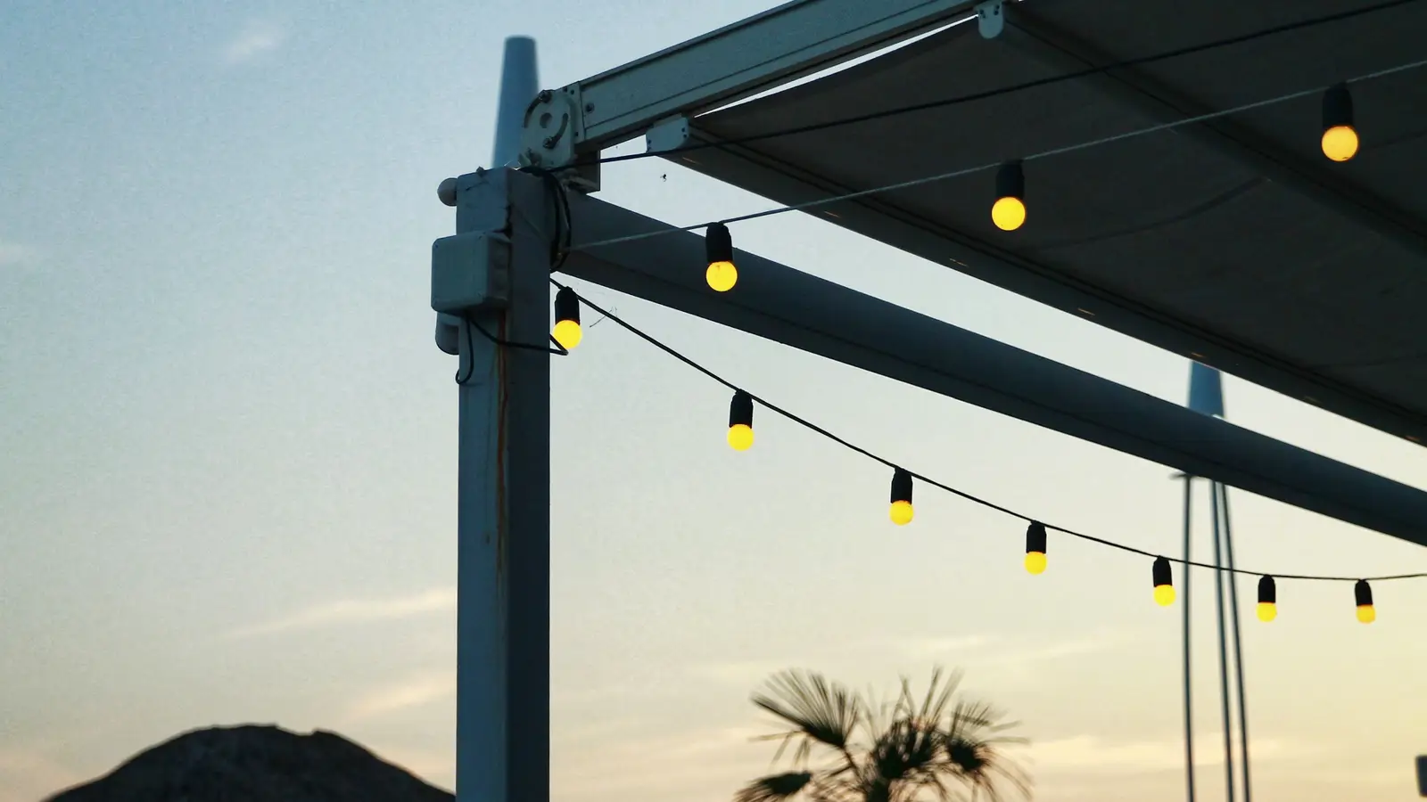 String lights hanging along a patio structure at sunset