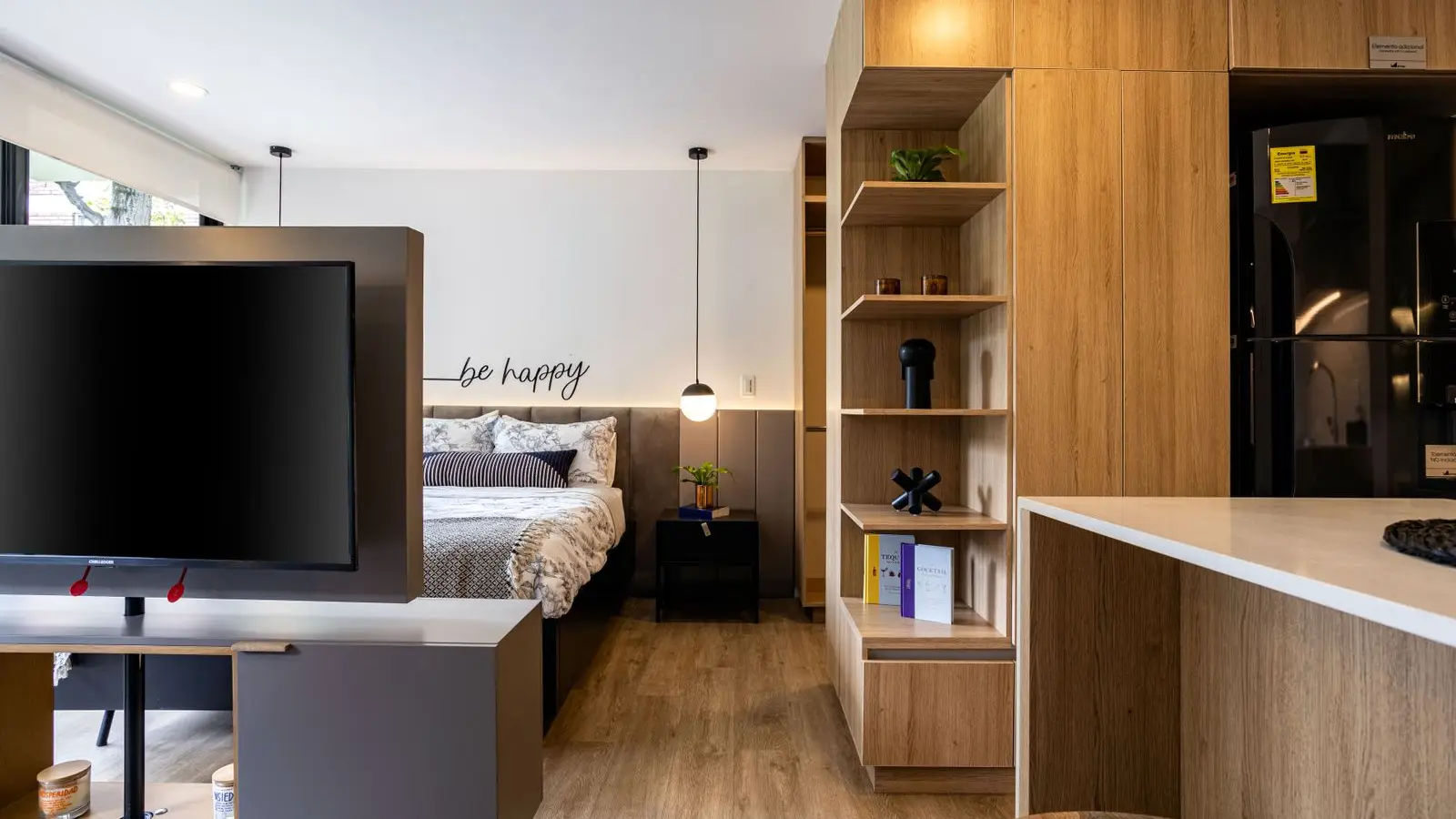 A furnished studio apartment with a shelving console dividing the bed area from the living space