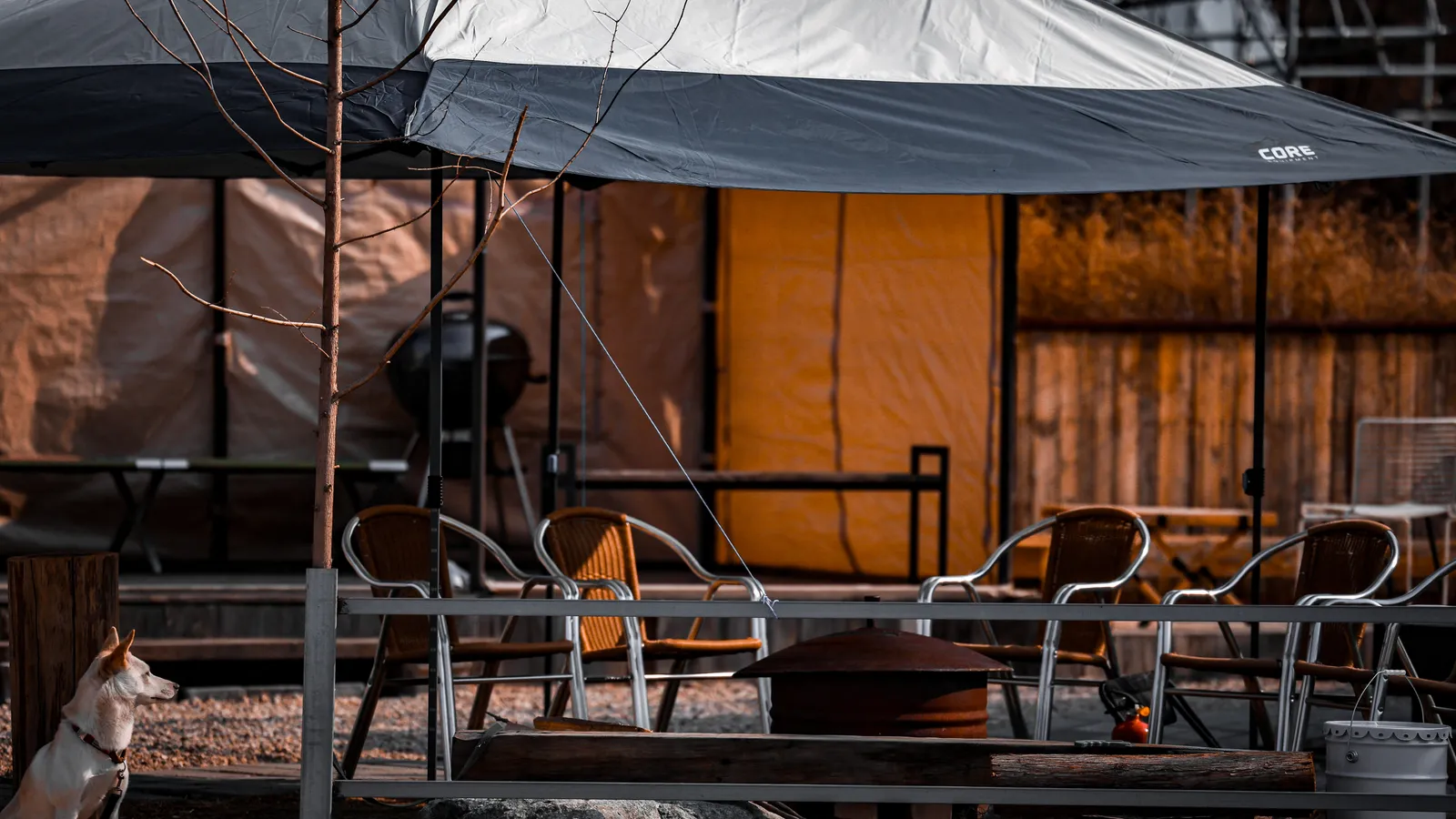 A casual pop-up canopy tent set up over patio seating in a backyard