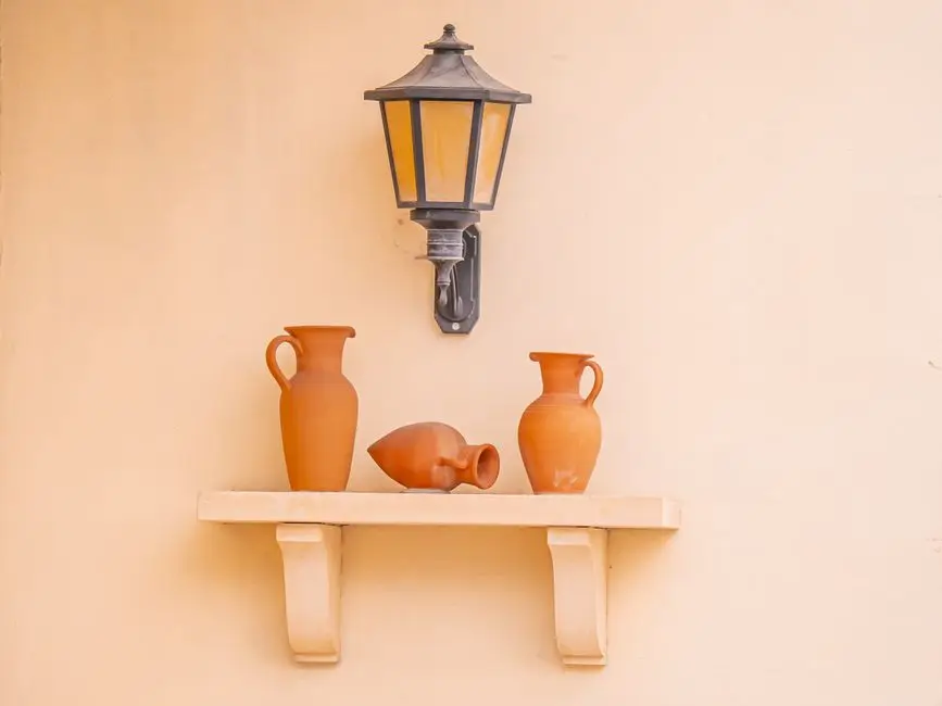 Terracotta ceramic vases and a lantern styled on a wall shelf, a keyword variation on organic modern decor ideas
