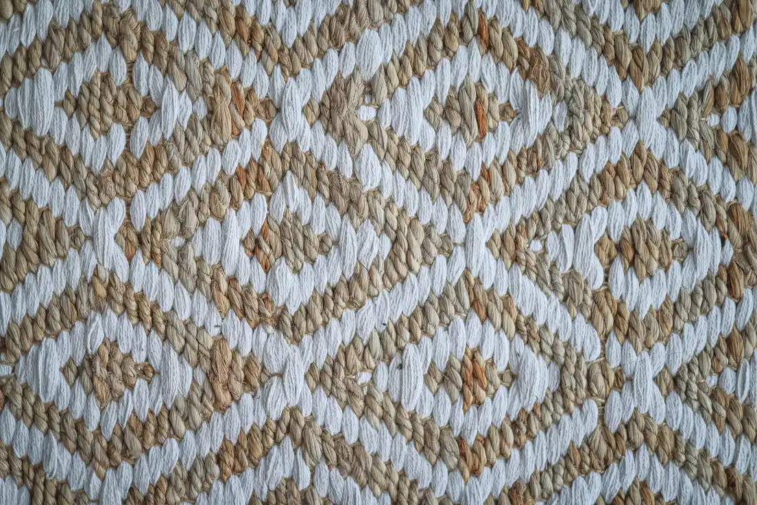 Close-up of a woven jute and cotton rug in a warm tan and cream diamond pattern