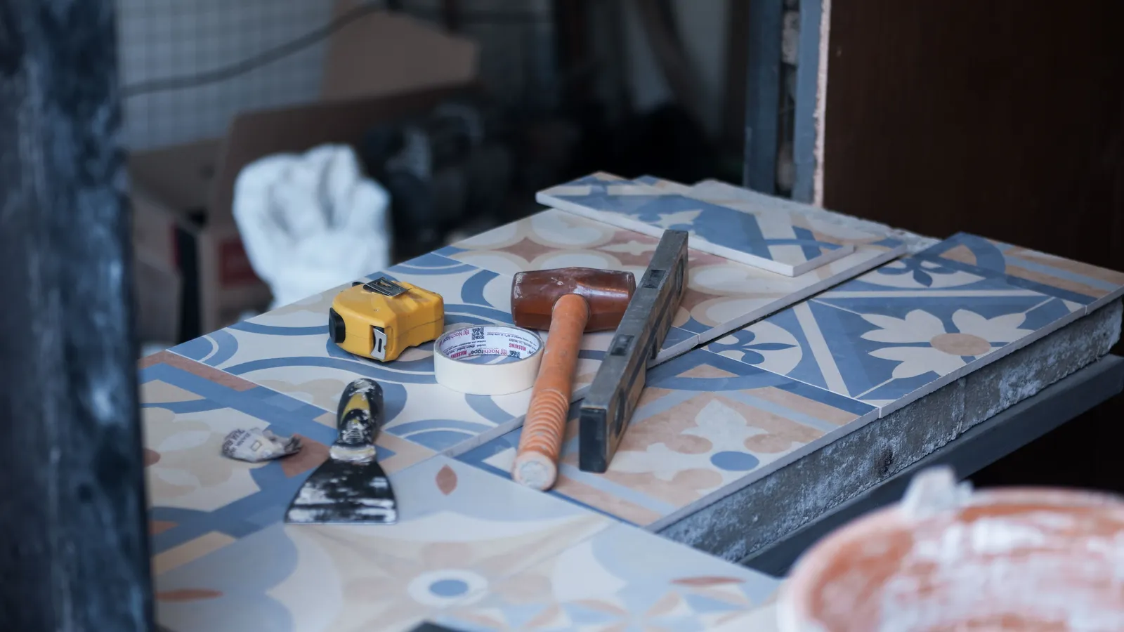 Tiling tools laid out including a tape measure, putty knife, and level for a peel and stick backsplash project