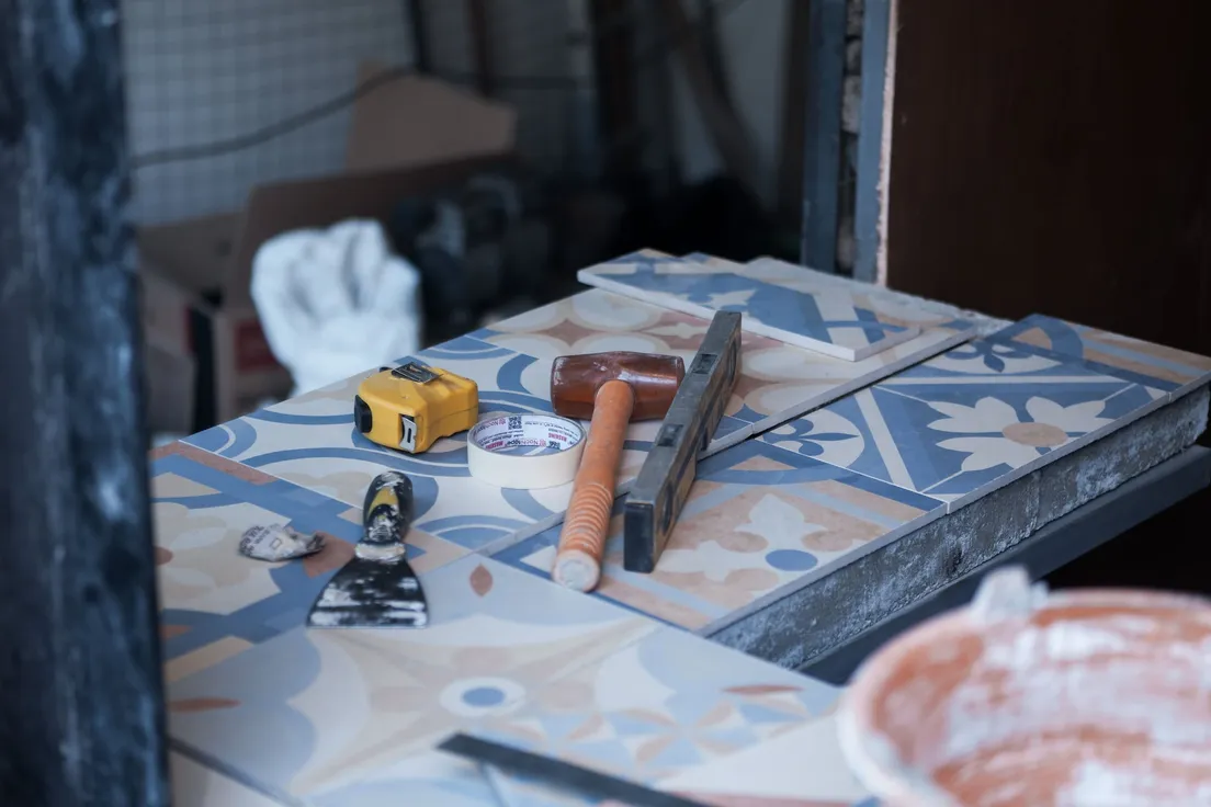 Tiling tools laid out including a tape measure, putty knife, and level for a peel and stick backsplash project