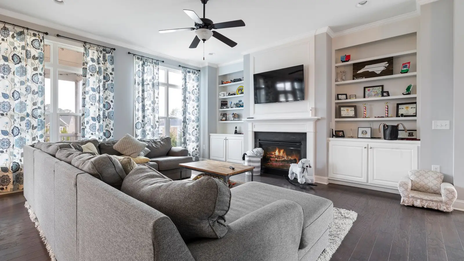 A gray sectional sofa sized to two-thirds of the living room wall near a fireplace and TV