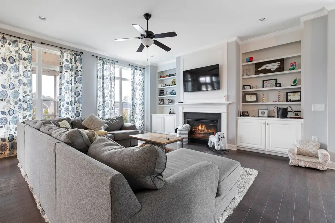 A gray sectional sofa sized to two-thirds of the living room wall near a fireplace and TV