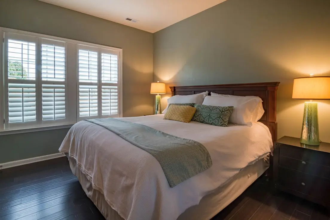 A bed positioned directly under a centered window in a small primary bedroom