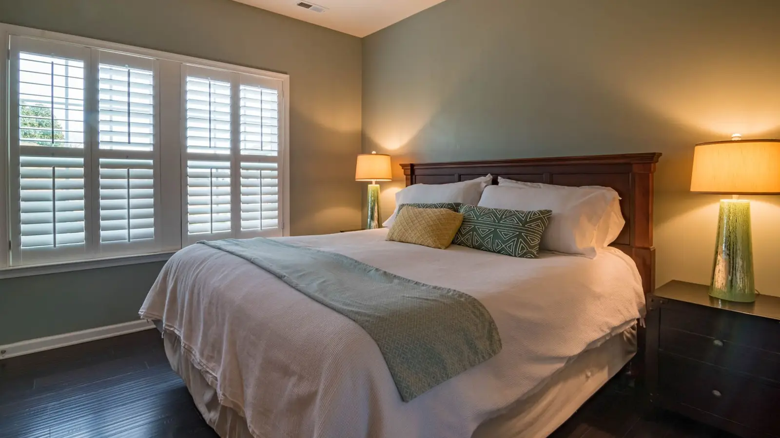 A bed positioned directly under a centered window in a small primary bedroom