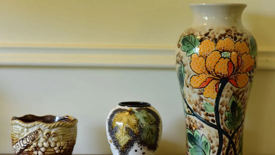 Three colorful hand-painted ceramic vases grouped on a wooden shelf