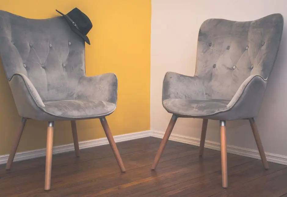 A pair of velvet tufted accent chairs against a mustard wall, an organic modern accent chair decor idea