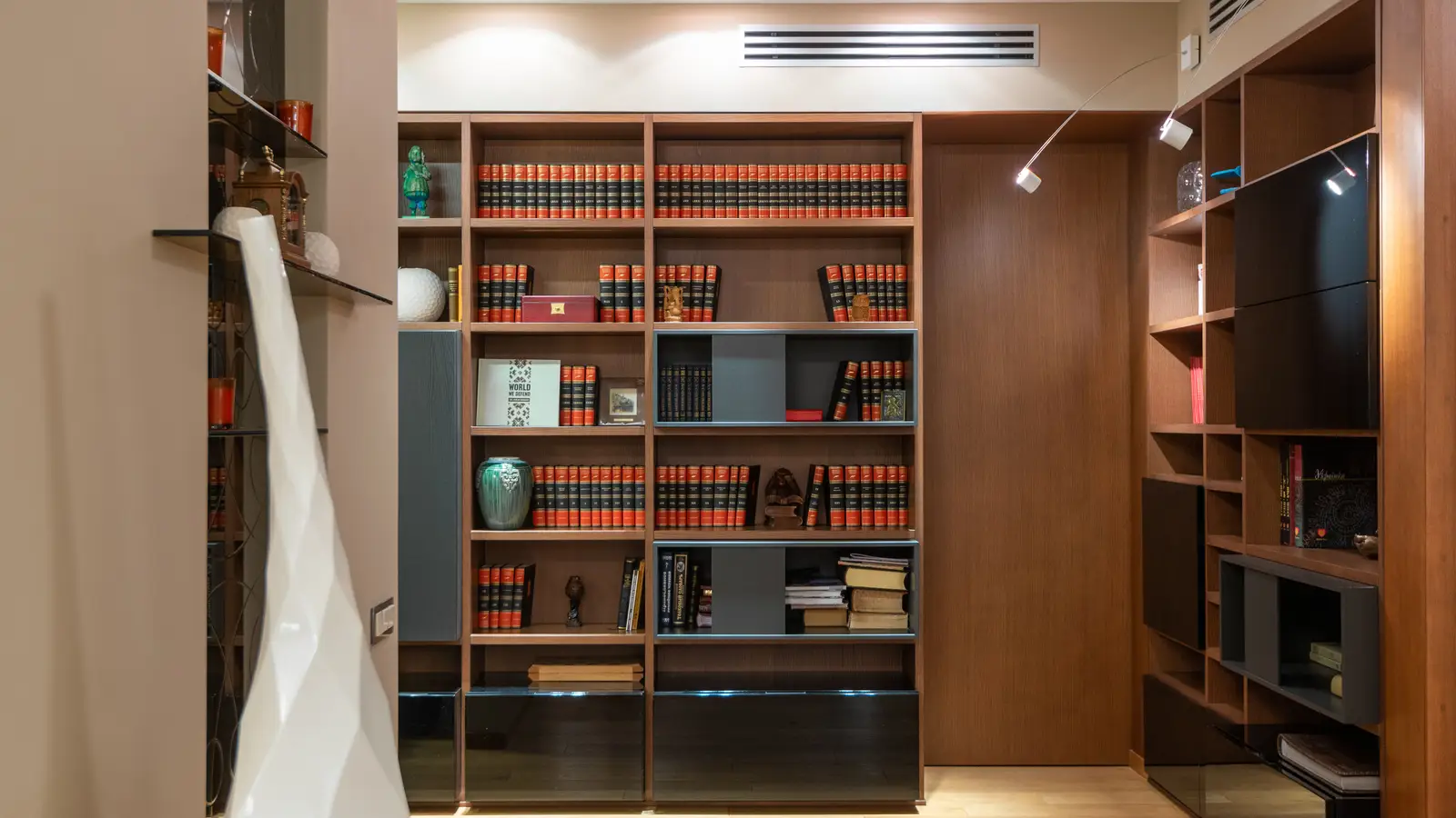 A floor-to-ceiling bookshelf used as vertical storage in a small apartment hallway