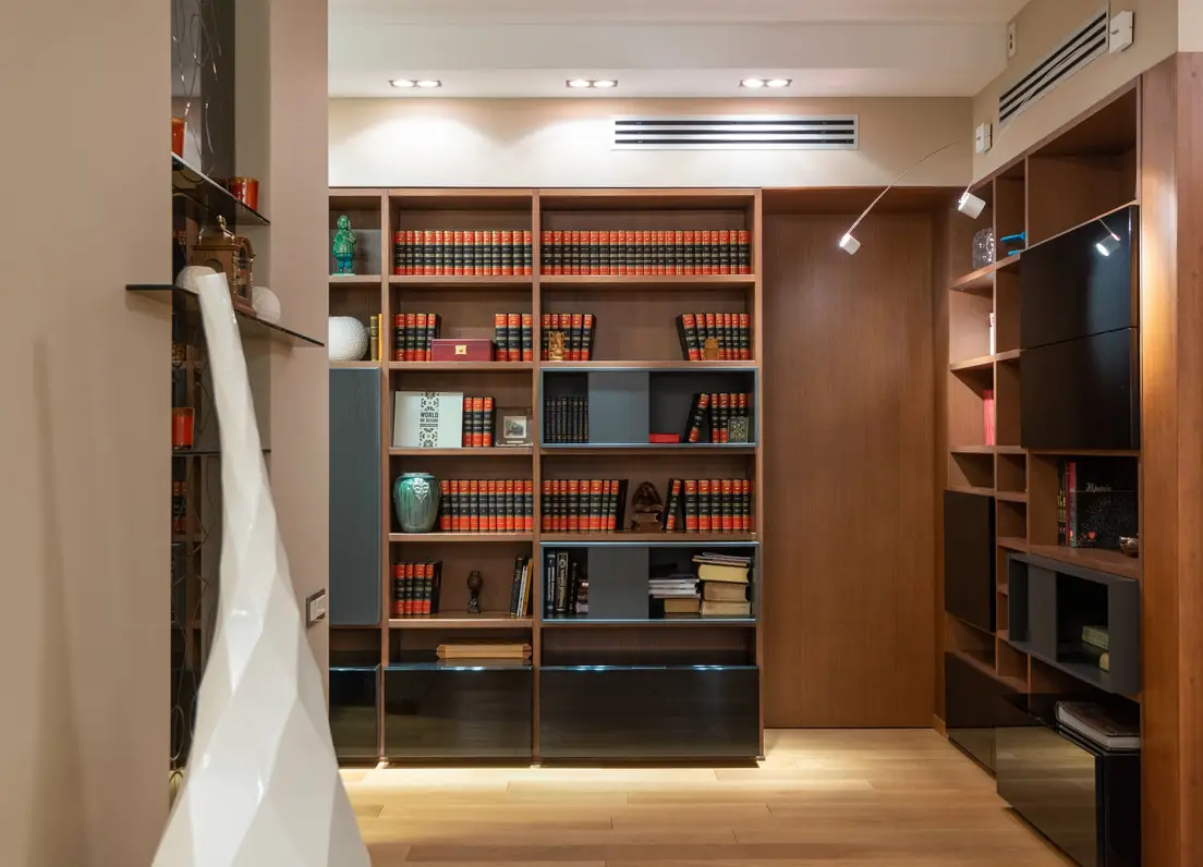 A floor-to-ceiling bookshelf used as vertical storage in a small apartment hallway