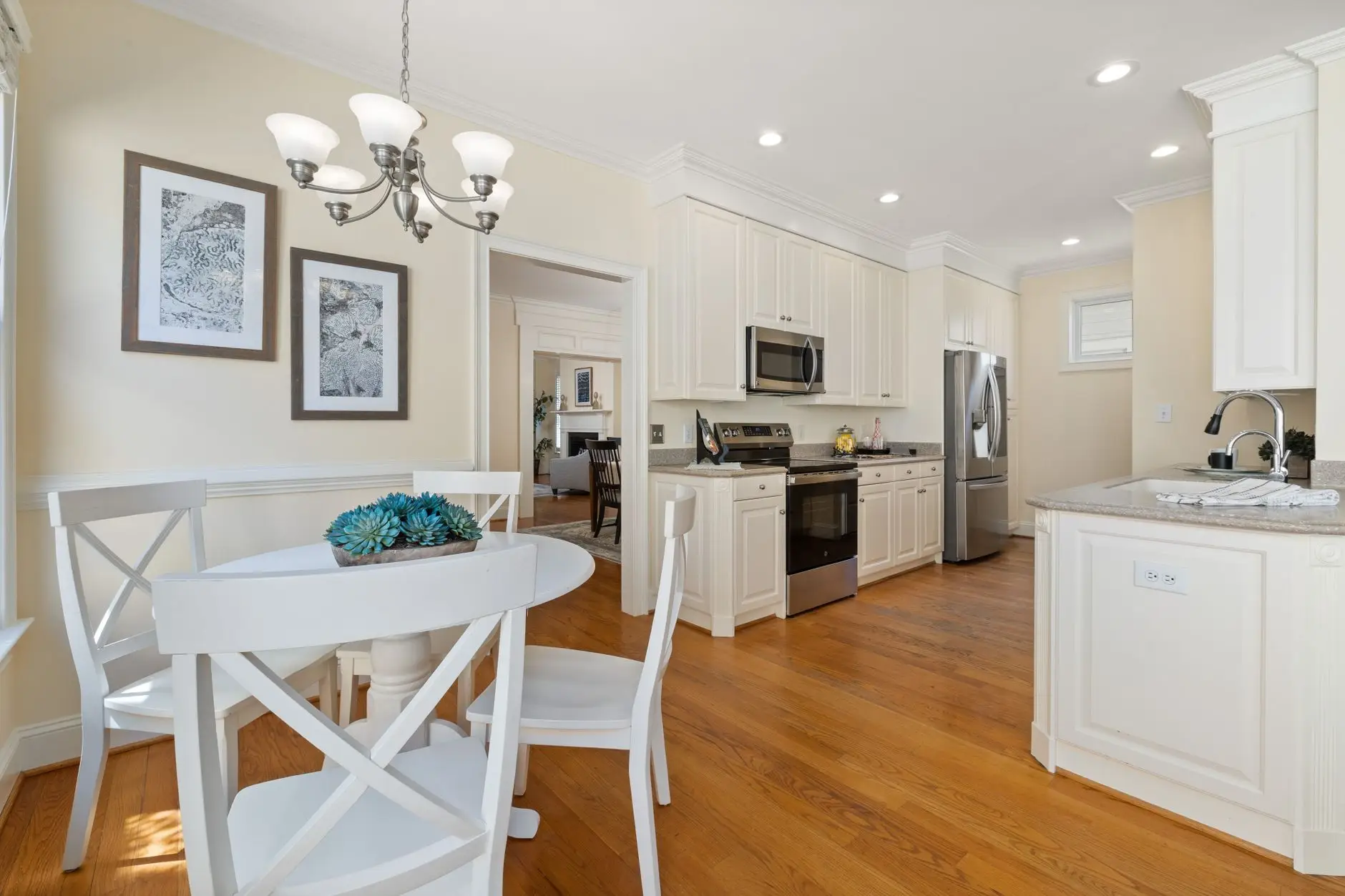 A bright kitchen dining nook with a round table and two framed art pieces on the wall