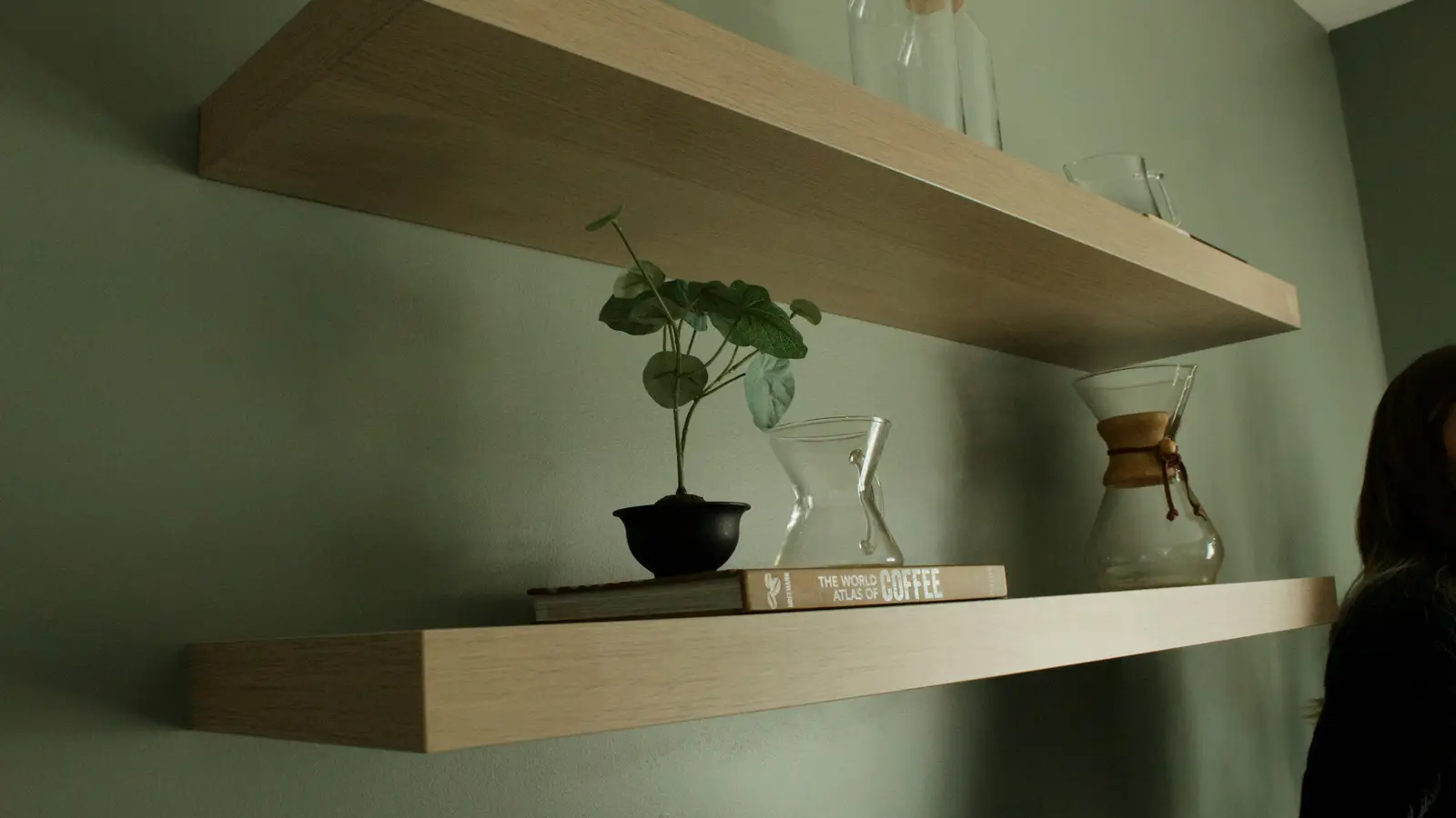 Two floating wall shelves styled with books and a plant, a small apartment idea for shelving instead of a bookcase