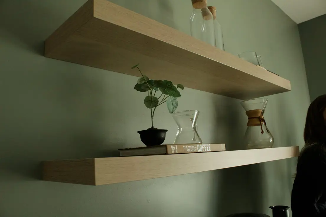 Two floating wall shelves styled with books and a plant, a small apartment idea for shelving instead of a bookcase