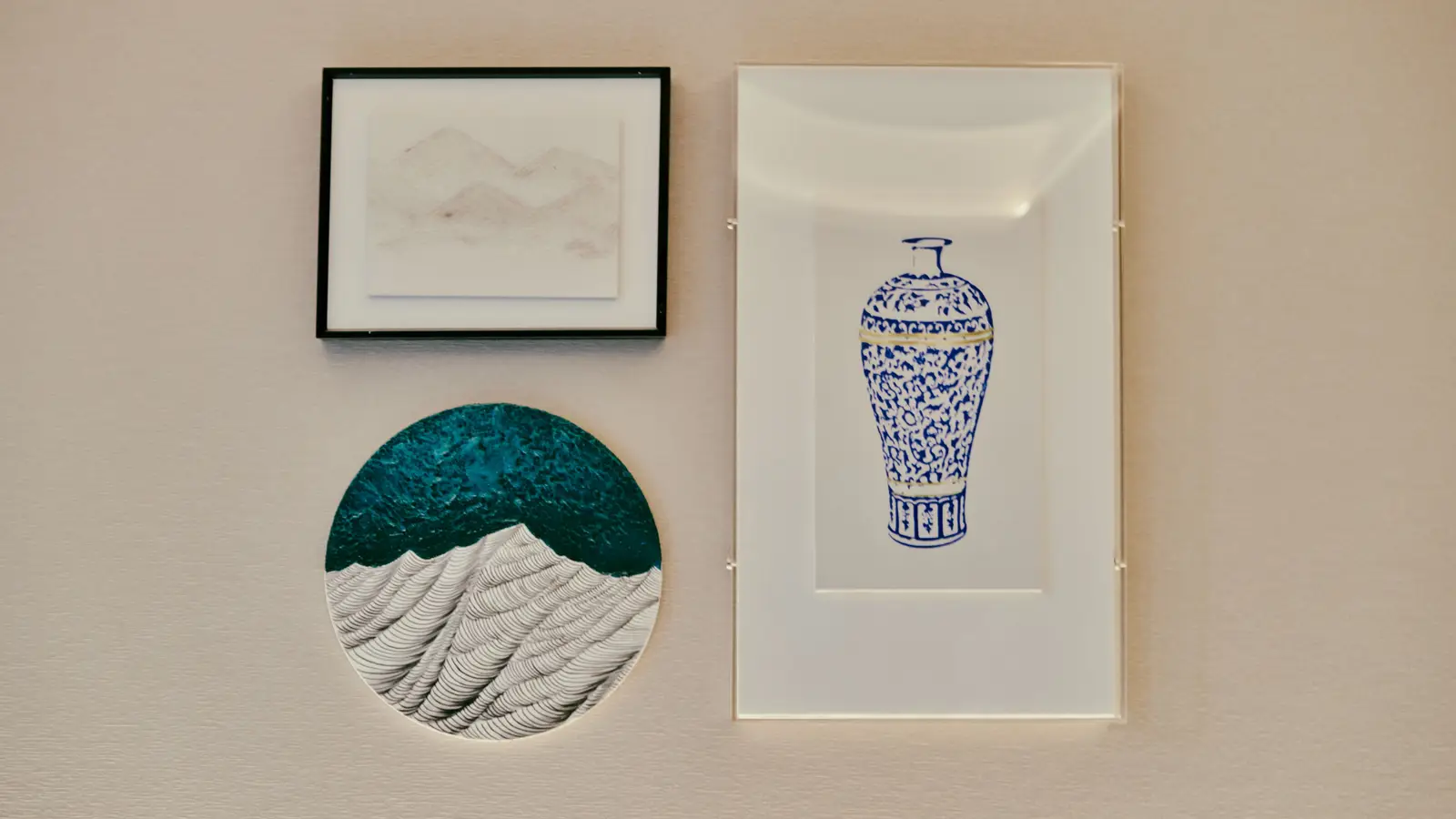 A minimalist gallery wall with one large framed print and two small sculptural art pieces