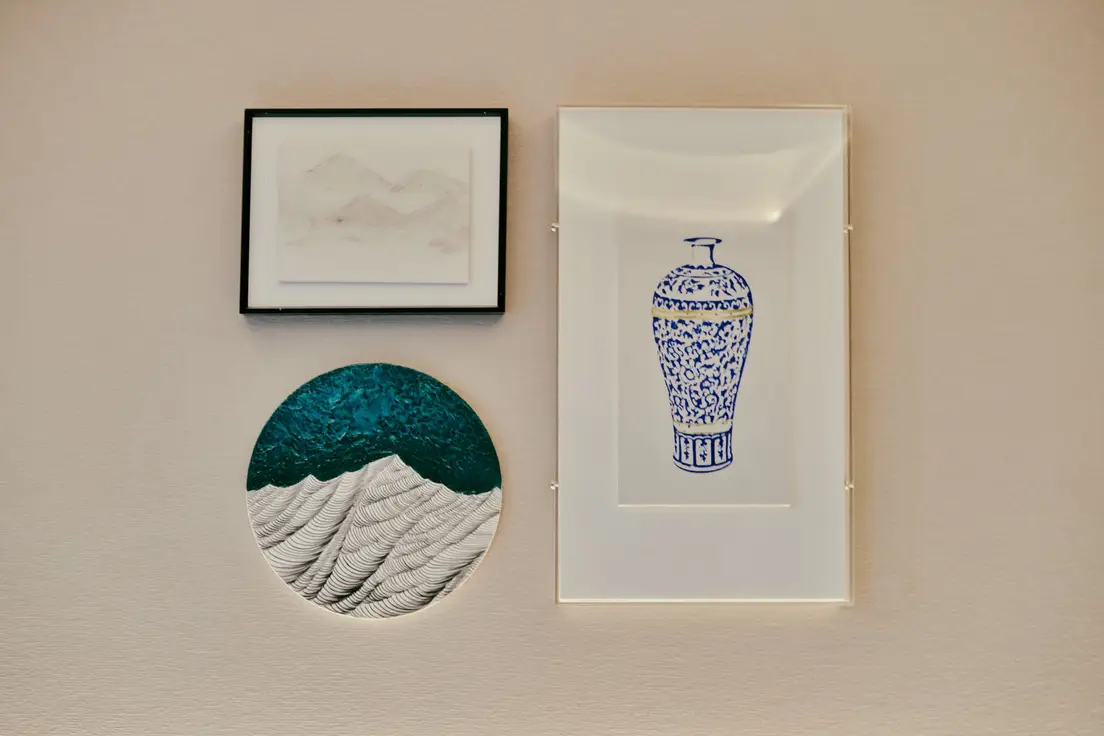 A minimalist gallery wall with one large framed print and two small sculptural art pieces