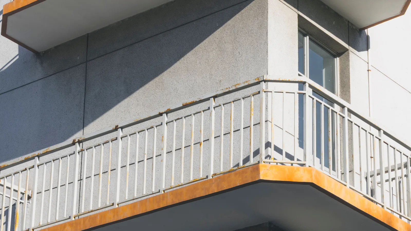 Close-up exterior view of stacked apartment building balconies with metal railings