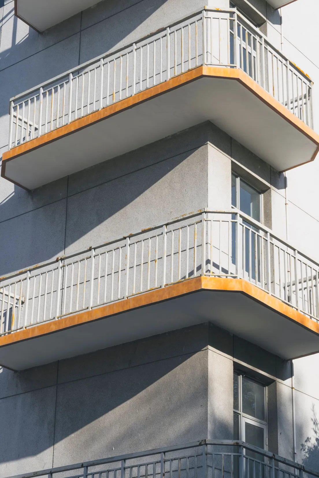 Close-up exterior view of stacked apartment building balconies with metal railings