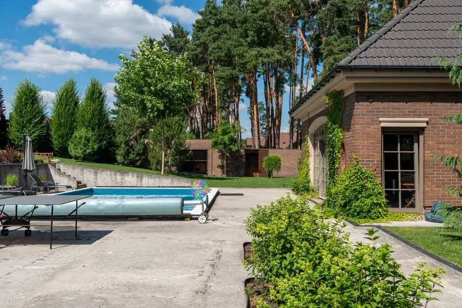 An uncovered concrete patio with no roof next to a backyard pool