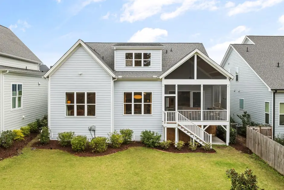 A house with a raised screened porch and stairs down to a ground-level backyard patio area