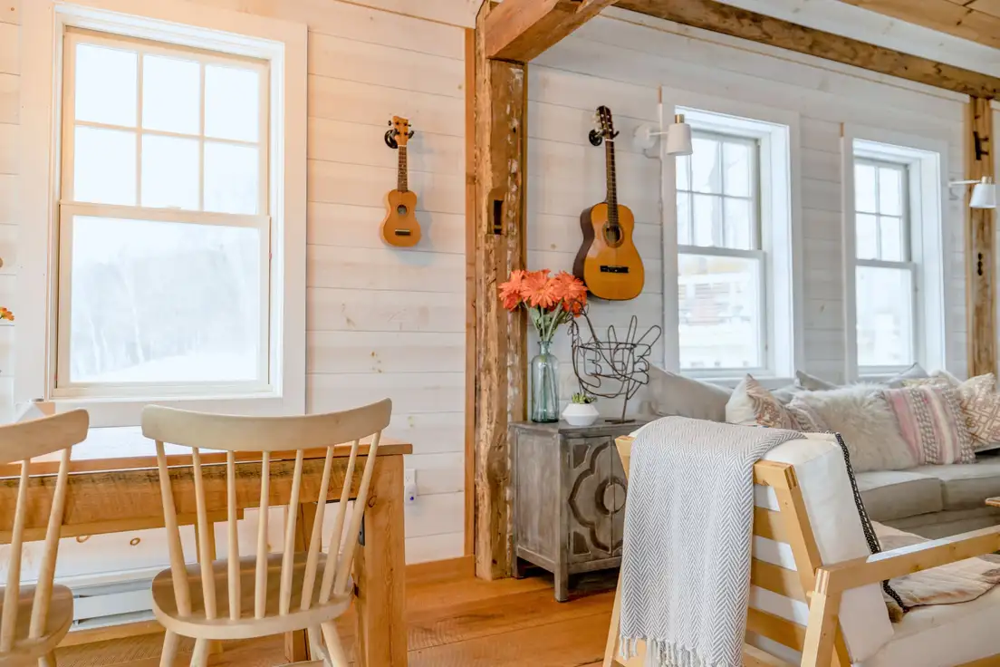 A white shiplap wall with rustic hand-hewn wood posts, double-hung windows, and a linen sofa in a farmhouse living room