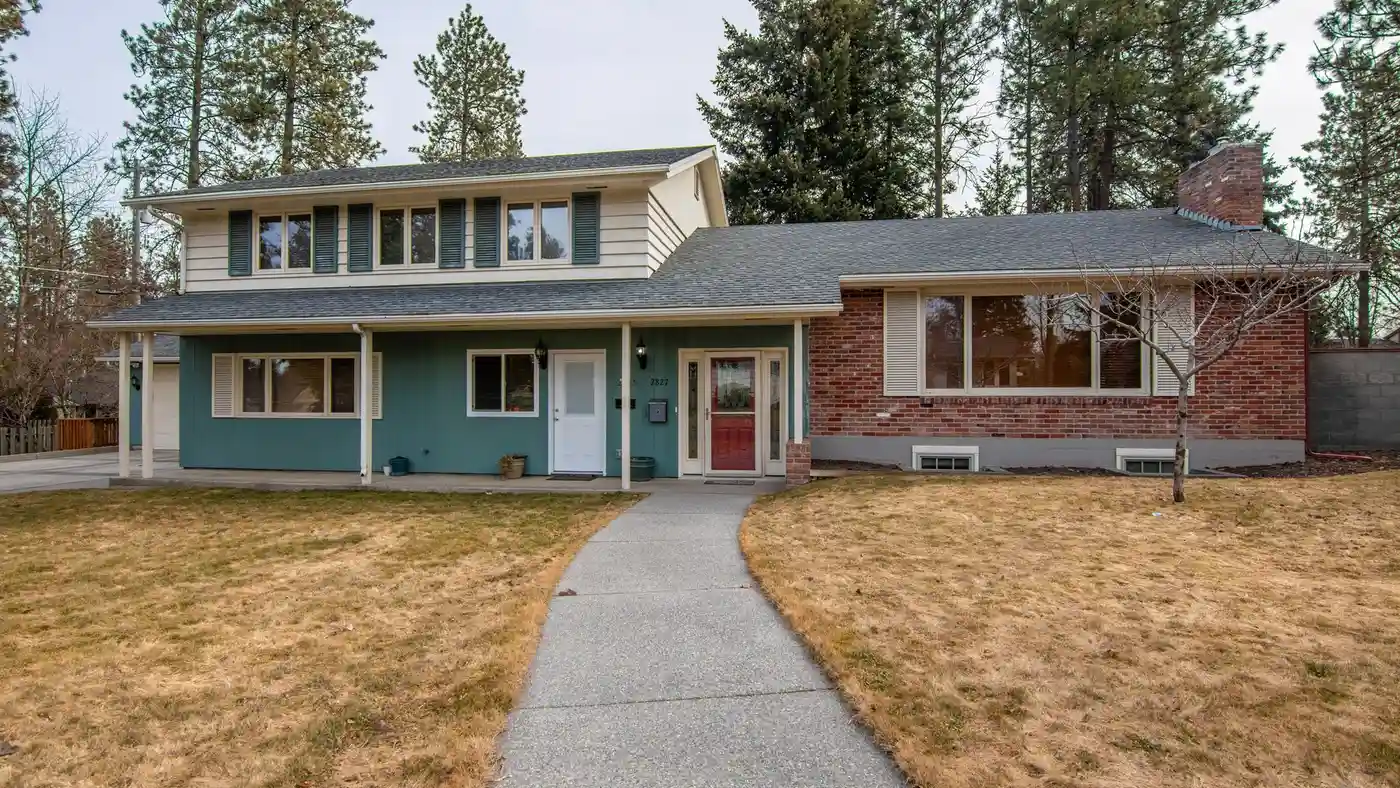 A split-level house exterior with a mix of brick and horizontal siding around double-hung windows