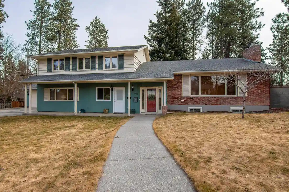 A split-level house exterior with a mix of brick and horizontal siding around double-hung windows