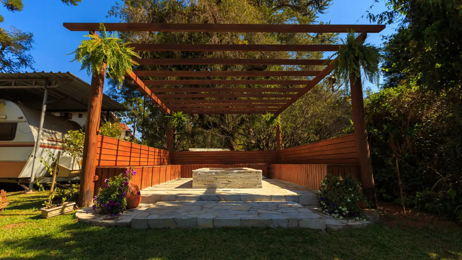 A wood-framed freestanding patio cover with exposed rafters in a backyard