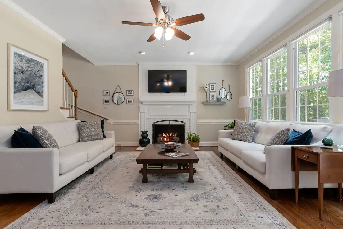 A dark rustic wooden coffee table between two white sofas on a pale vintage-style rug in a farmhouse living room with a fireplace