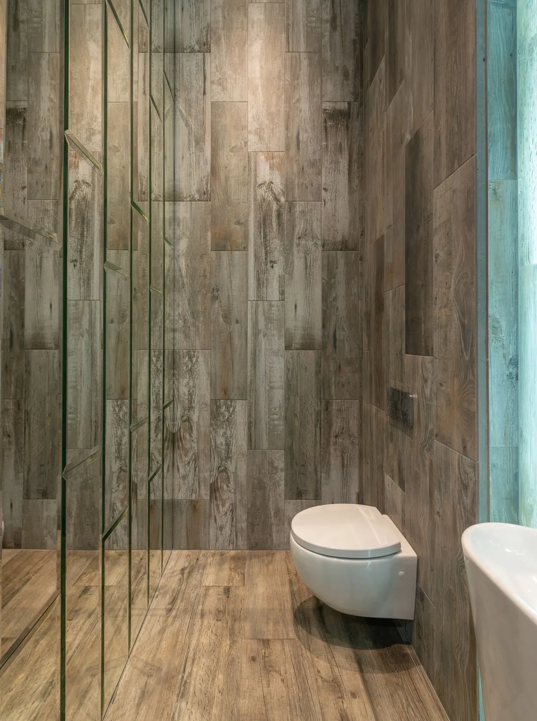 A minimalist bathroom with vertical wood-look plank tile covering the walls floor to ceiling