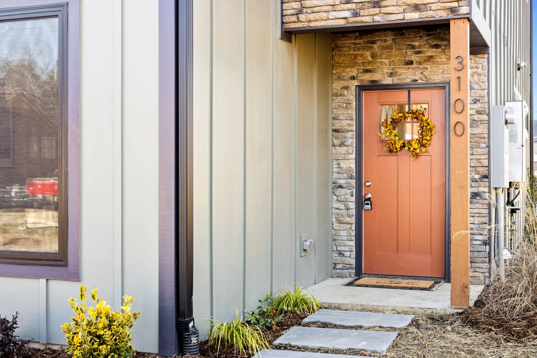 A stacked-stone and cedar accent around a modern farmhouse exterior front door