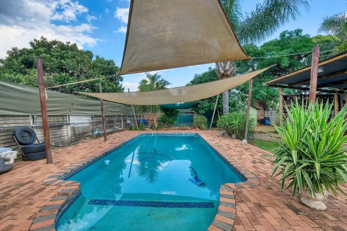 Two tan shade sails stretched over a backyard pool as a low-cost patio cover alternative